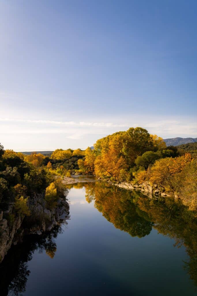Rivière sinueuse bordée d'arbres aux couleurs de la foliage season dans une nature préservée.