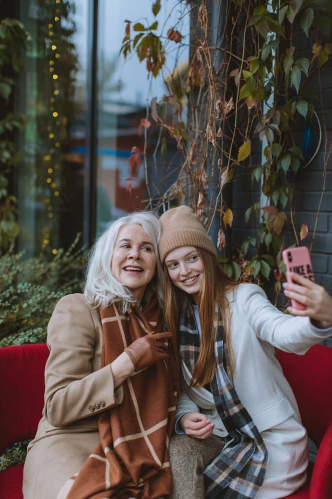 Sourires partagés lors d'un selfie en duo grand-mère/ petite fille dans un décor urbain illuminé par la foliage season