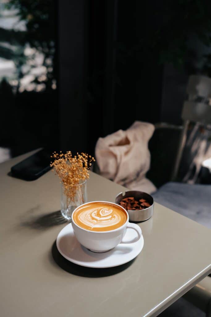 Tasse de café latte art posée sur une table lors d'une douce pause de foliage season.