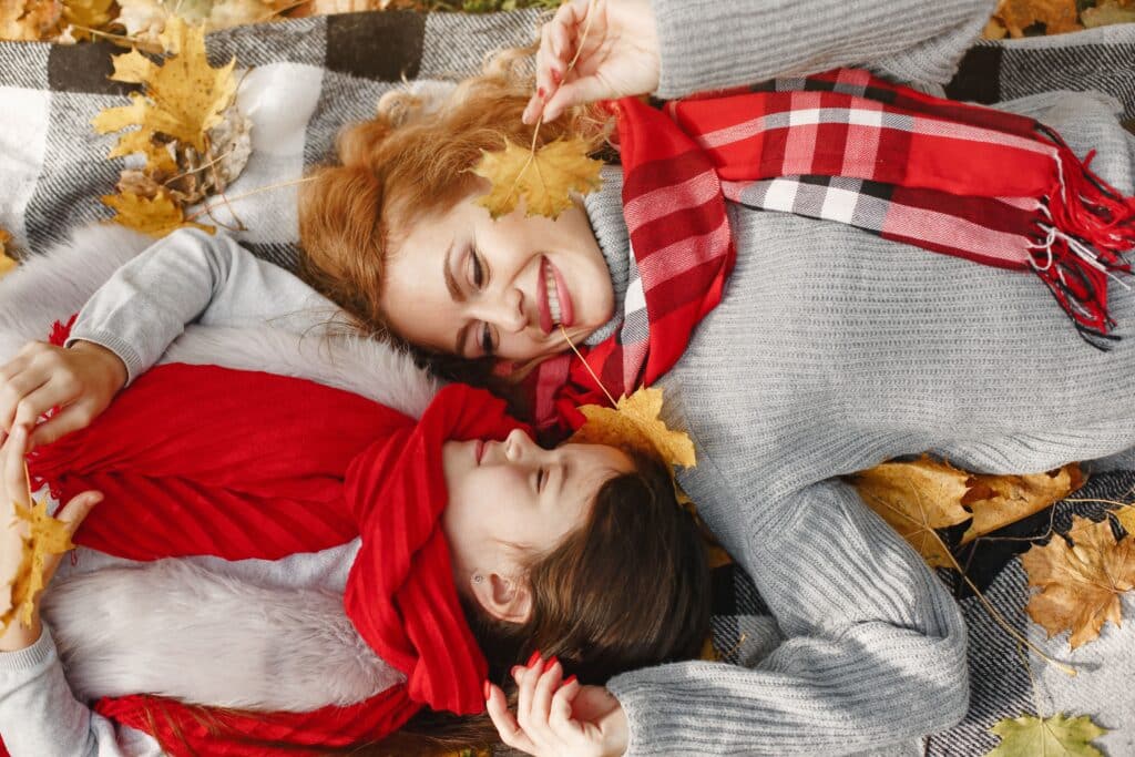 Moment de complicité partagé par un duo mère-fille blotti sous un plaid au cœur de la foliage season