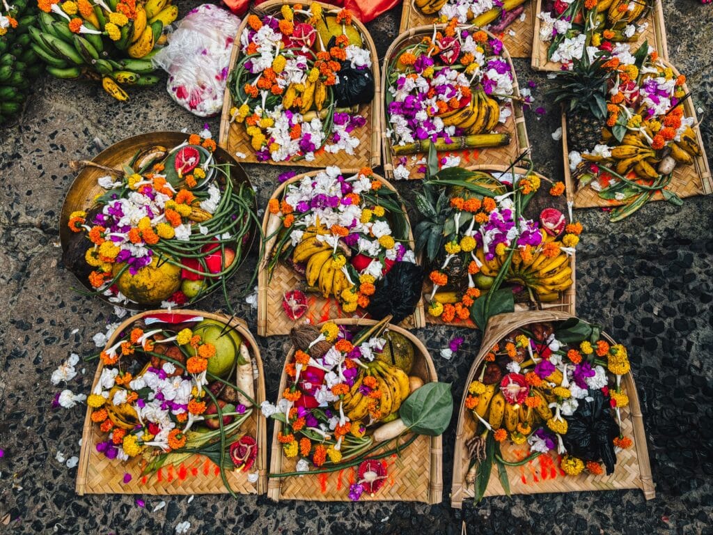 Gros plan sur des offrandes traditionnelles balinaises (Canang sari) tressées en feuilles de palmier et décorées de fleurs colorées pour une cérémonie religieuse à Bali.