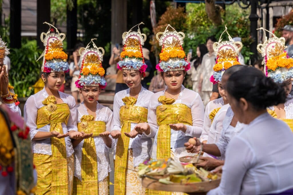 Procession animée et danseuses traditionnelles en costumes de cérémonie lors d'une crémation (Ngaben) festive à Bali.