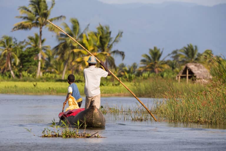 Texte alternatif : Immersion à Madagascar avec une pirogue naviguant sur l'eau, illustrant l'esprit de partage et le Fihavanana au cœur des paysages locaux.