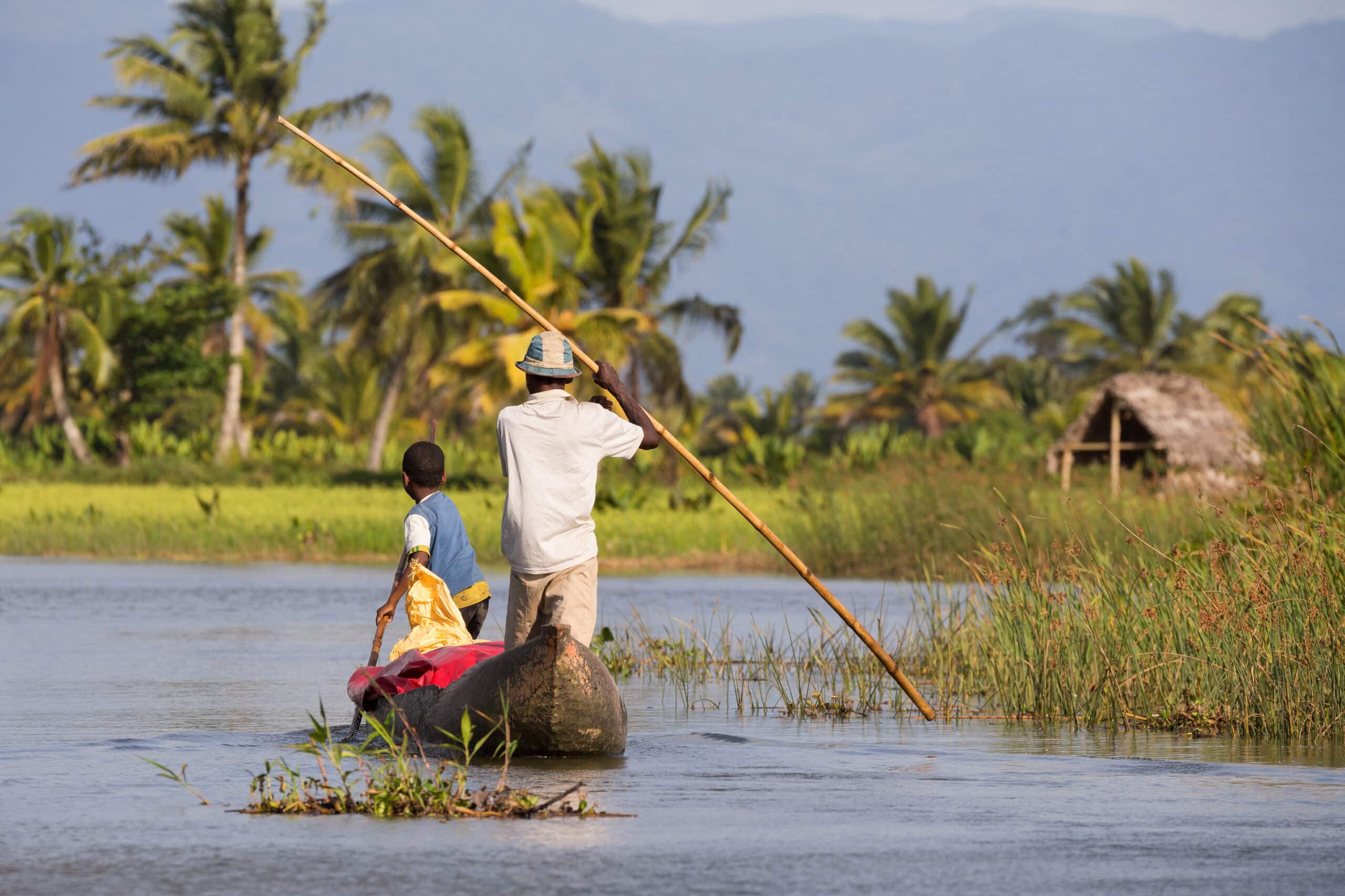 Texte alternatif : Immersion à Madagascar avec une pirogue naviguant sur l'eau, illustrant l'esprit de partage et le Fihavanana au cœur des paysages locaux.