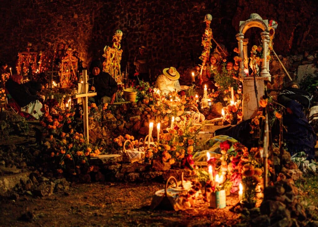 Scène de veillée dans un cimetière mexicain la nuit, avec des familles assises près des tombes décorées d'une profusion de fleurs de cempasúchil et d