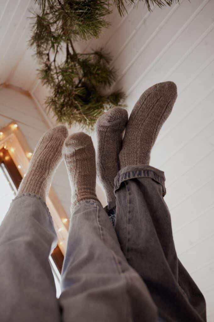 Pieds en chaussettes en maille bien au chaud près du feu, l'image parfaite du hygge et du bonheur danois partagé