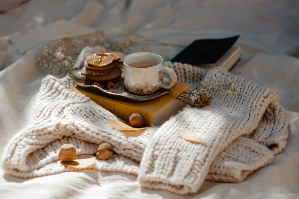 Scène hygge chaleureuse avec une tasse de boisson chaude, des pâtisseries et un plaid en laine, symbole du bonheur danois en duo