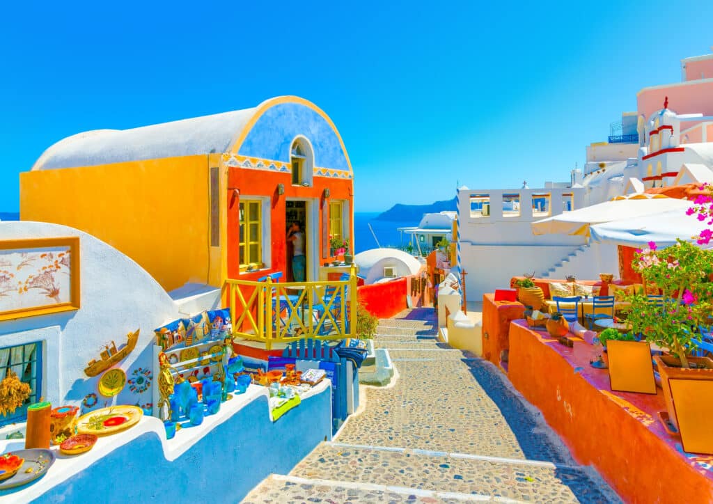 Ruelle pittoresque aux teintes colorées de Santorin surplombant la mer Égée, voyage sur-mesure en duo Heaven Collection.