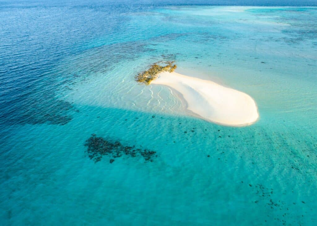 Vue aérienne d'un banc de sable blanc et eau turquoise à Madagascar, une escapade paradisiaque pour un voyage en duo sur mesure.