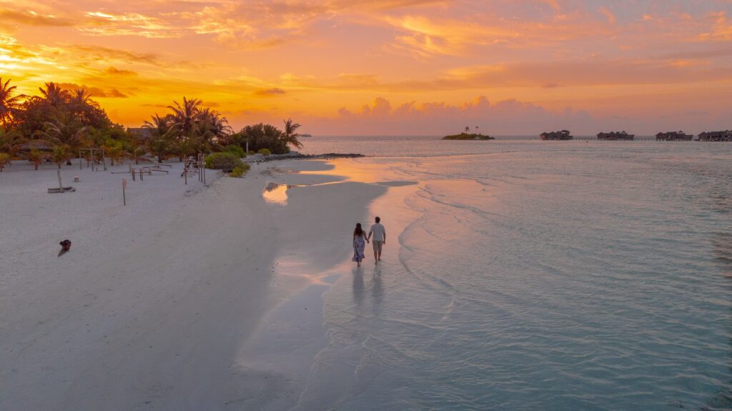 Couple en voyage marchant sur une plage au coucher du soleil lors d’une Parenthèse sur mesure Heaven Collection