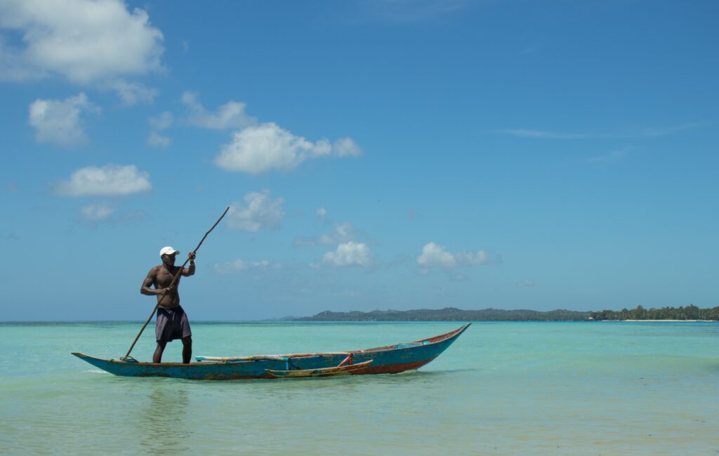 Navigation en pirogue sur les eaux turquoise de Madagascar, incarnant la sérénité et les valeurs du Fihavanana.