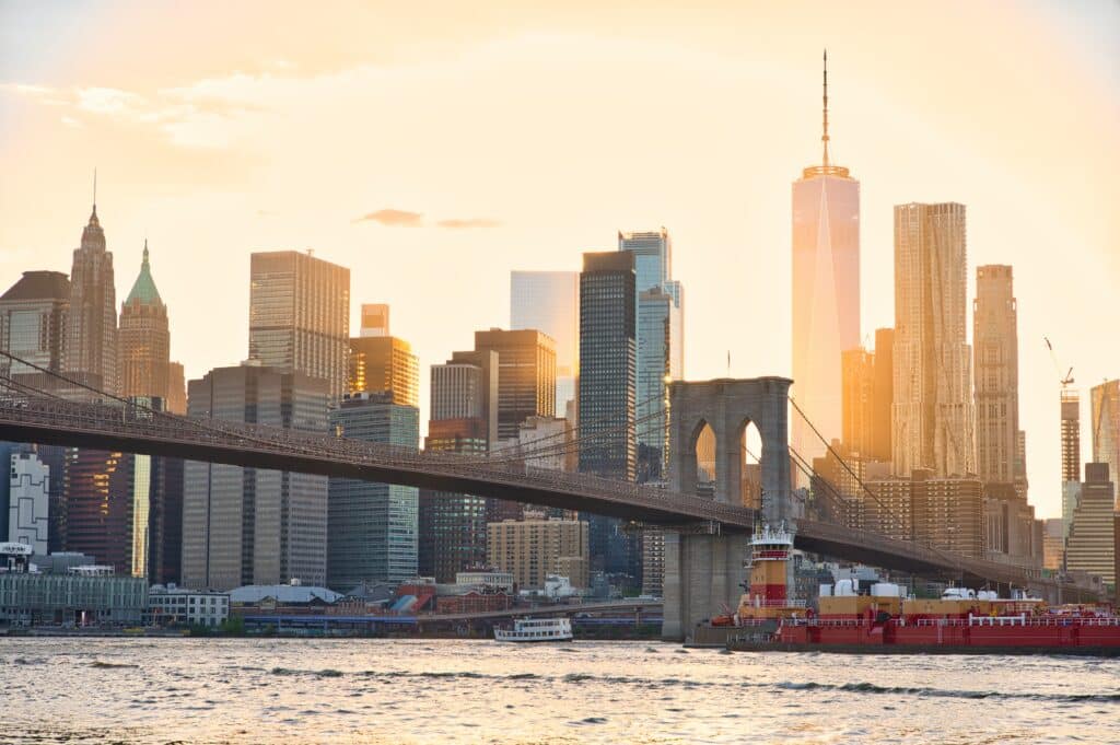 Panorama de la skyline de Manhattan et du pont de Brooklyn à New York sous une lumière dorée, invitation à un voyage d'exception aux États-Unis.