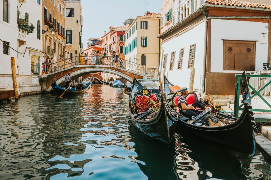 Charme pittoresque d'un canal étroit à Venise, traversé par un petit pont de pierre et animé par le passage des gondoles. Un cadre propice au romantisme.