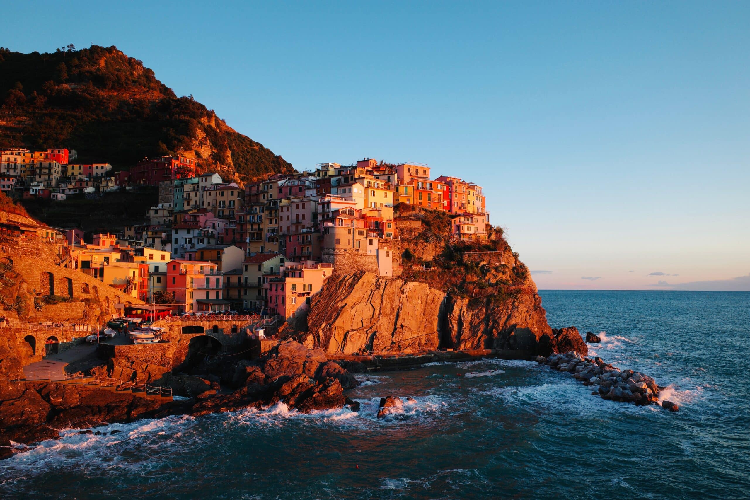Vue panoramique des falaises colorées des Cinque Terre en Italie au coucher du soleil, symbole d'un voyage romantique et sur-mesure en Italie.