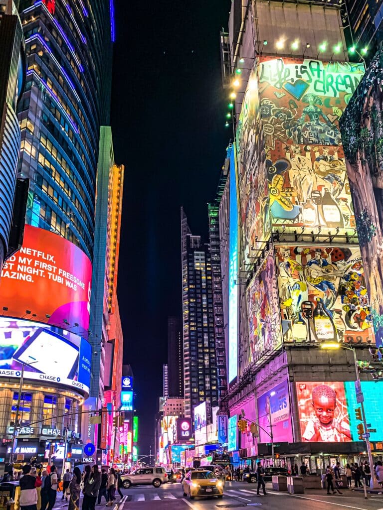 Écrans géants lumineux et ambiance électrique de Times Square de nuit à New York, le chaos fascinant orchestré par Heaven Collection.