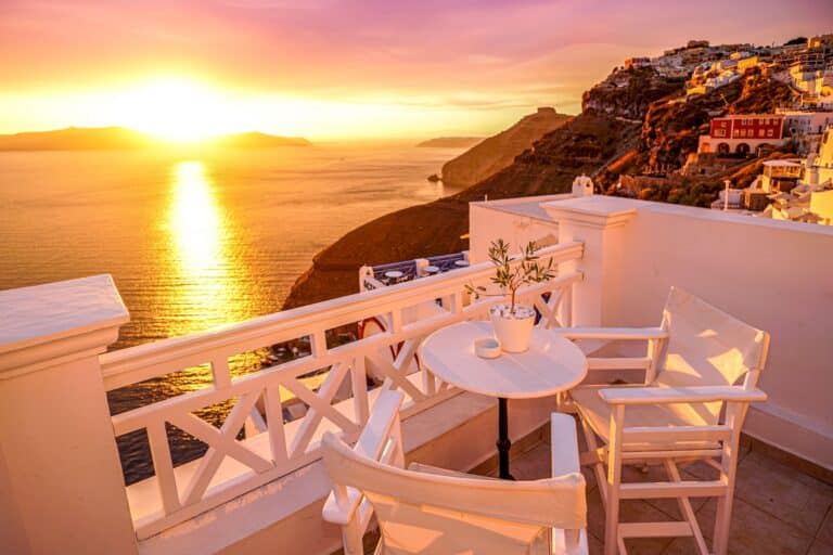 Terrasse lumineuse avec table et deux fauteuils en rotin, entourée de bougainvilliers.
