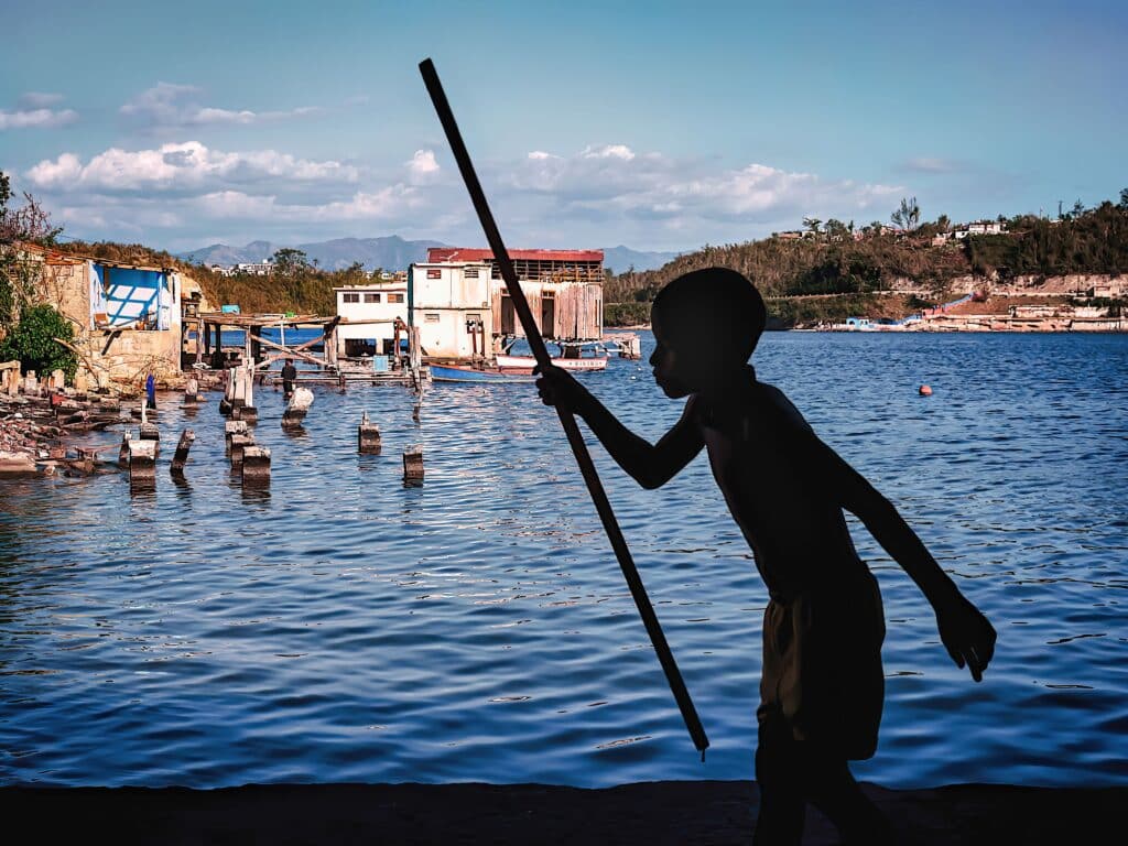 Scène de vie quotidienne à Madagascar, où un enfant contemple l'eau, symbole de la simplicité et du Fihavanana qui caractérisent l'île.
