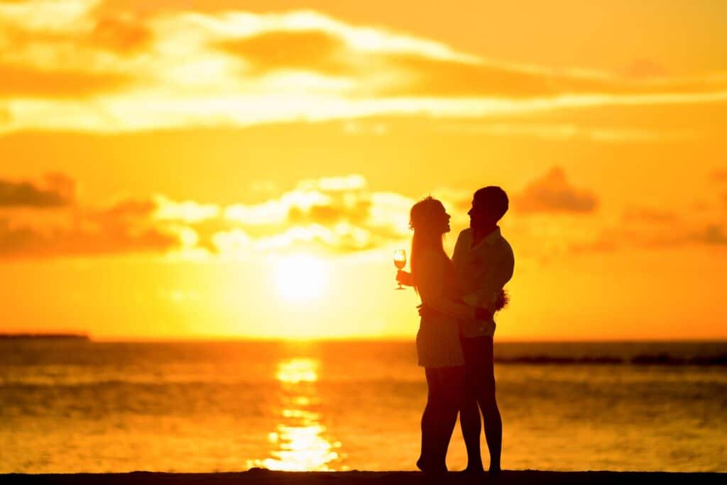 Deux personnes au bord de la mer devant un coucher de soleil.