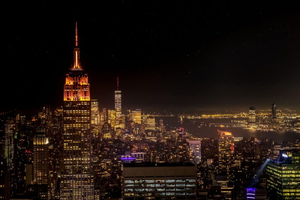 Vue nocturne de New York avec l’Empire State Building illuminé et les lumières de Manhattan.