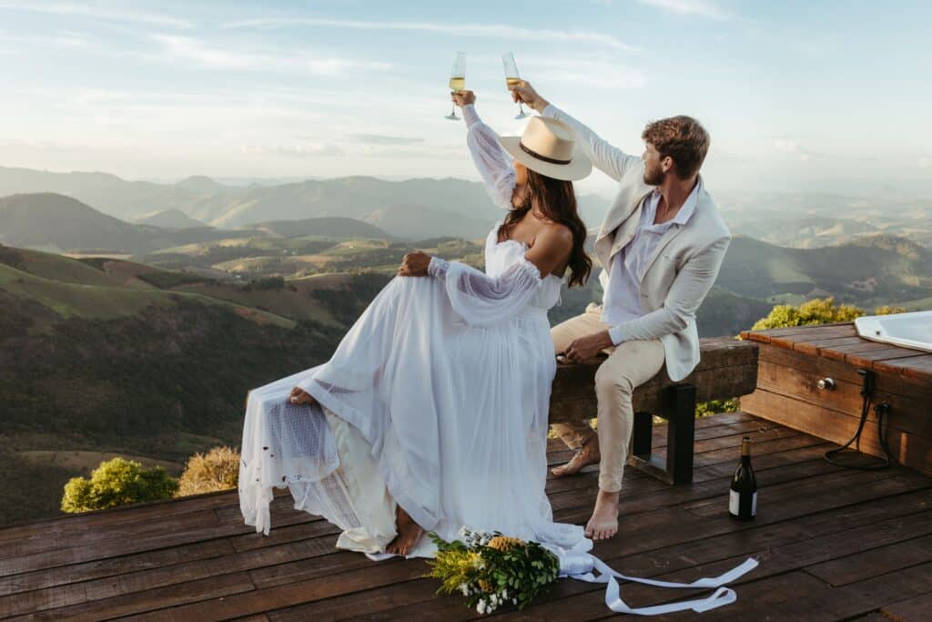 Deux personnes levant leurs verres lors d'une Parenthèse Célébration face à un vaste paysage de montagnes.