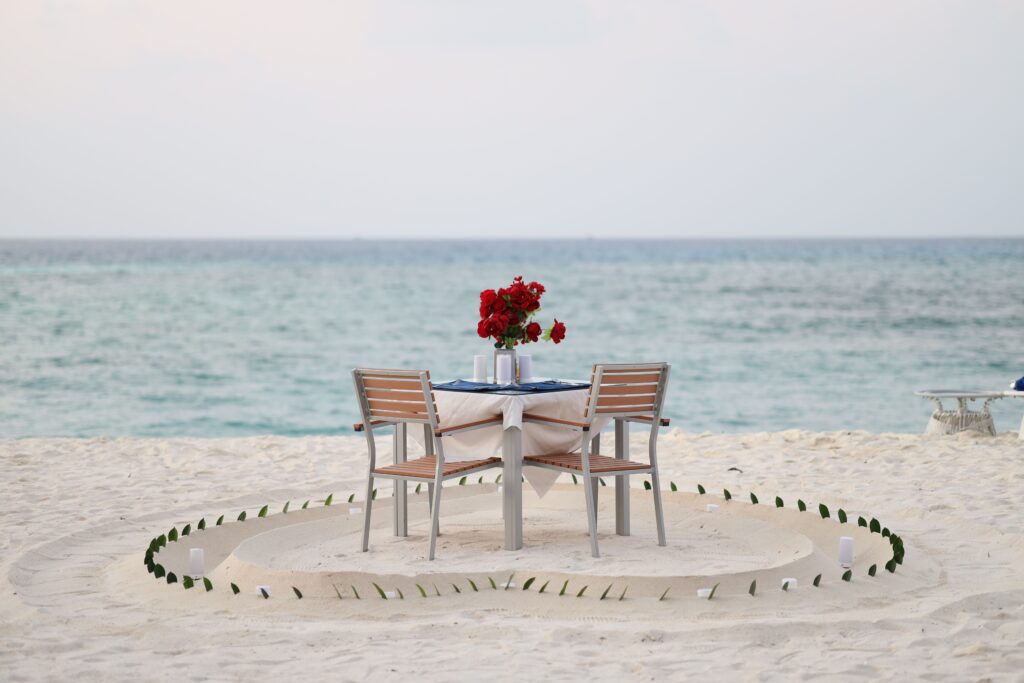Table dressée pour deux sur une plage face à la mer.