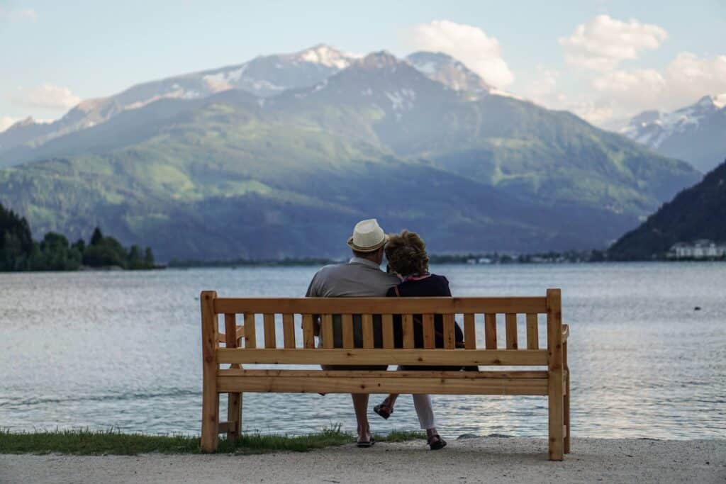 Deux personnes assises sur un banc face à un lac et aux montagnes lors d'une Parenthèse Évasion
